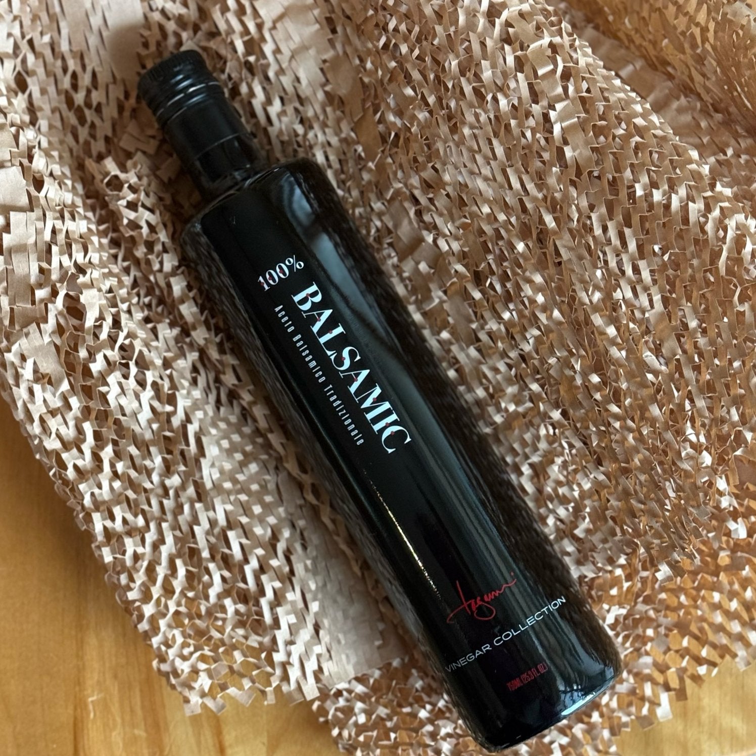 A big 750 ml bottle of Balsamic Vinegar rests nestled in kraft eco-friendly packing paper