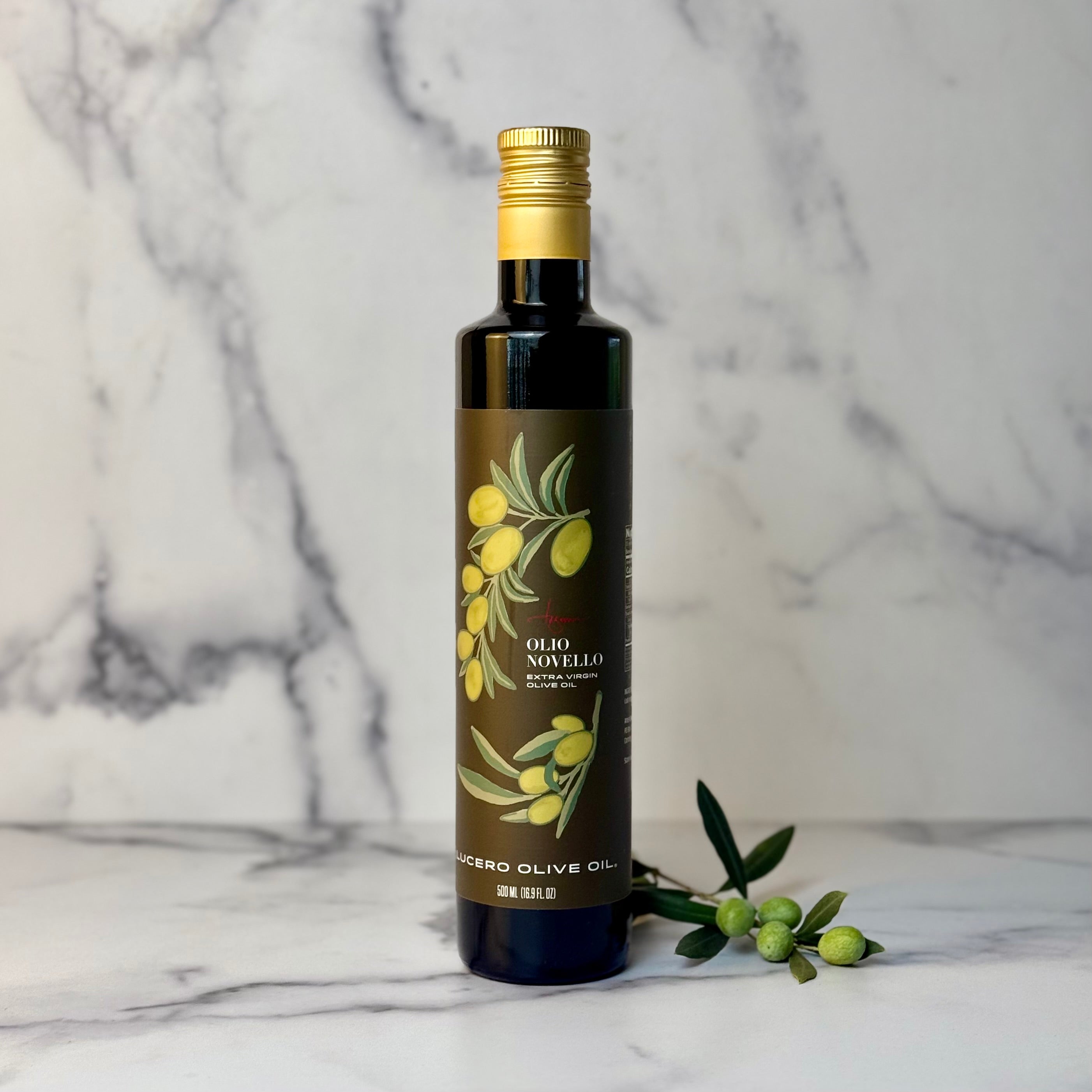Bottle of Lucero Olio Novello olive oil with a gold cap on a marble surface