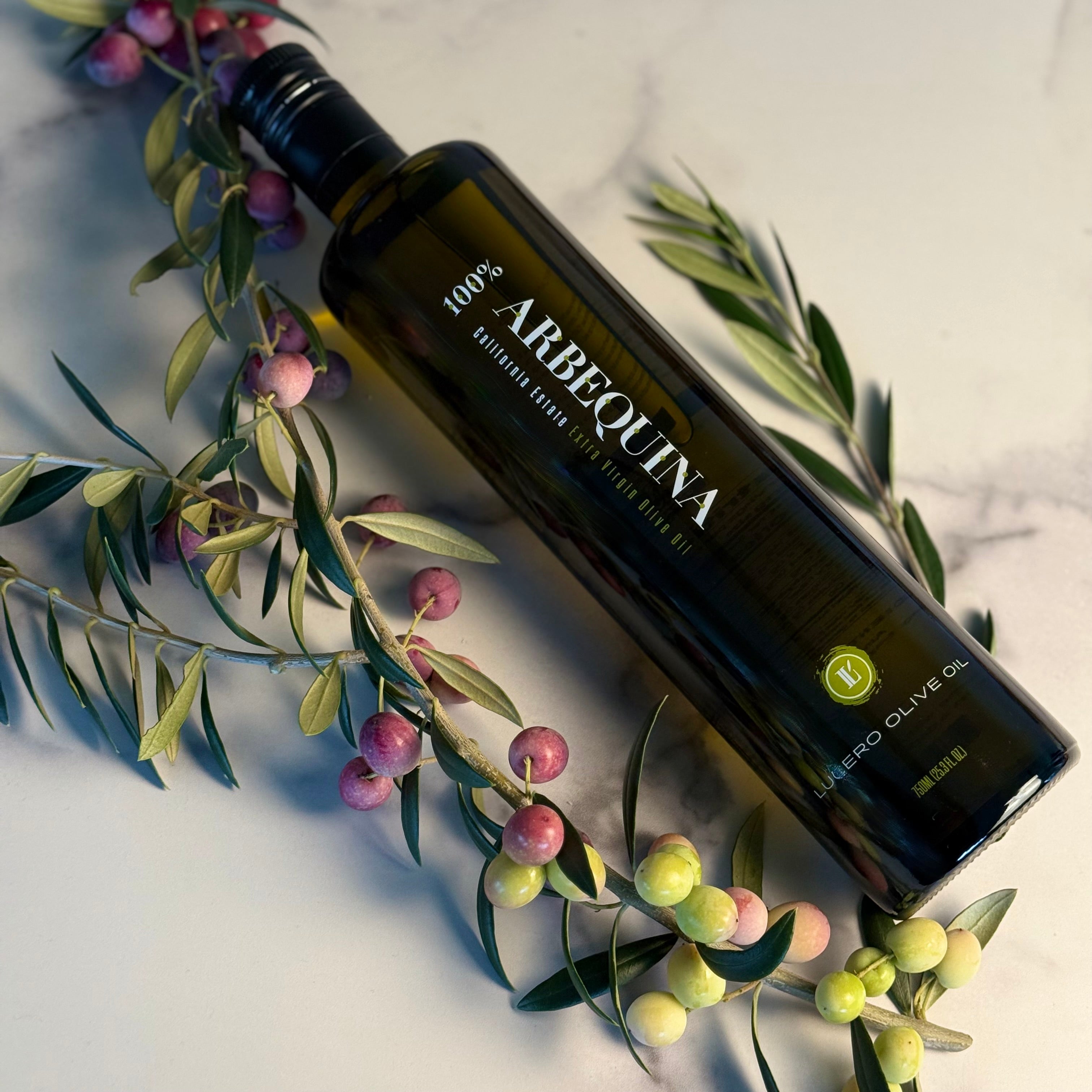 Bottle of Arbequina olive oil with olive branches and olives on a light background