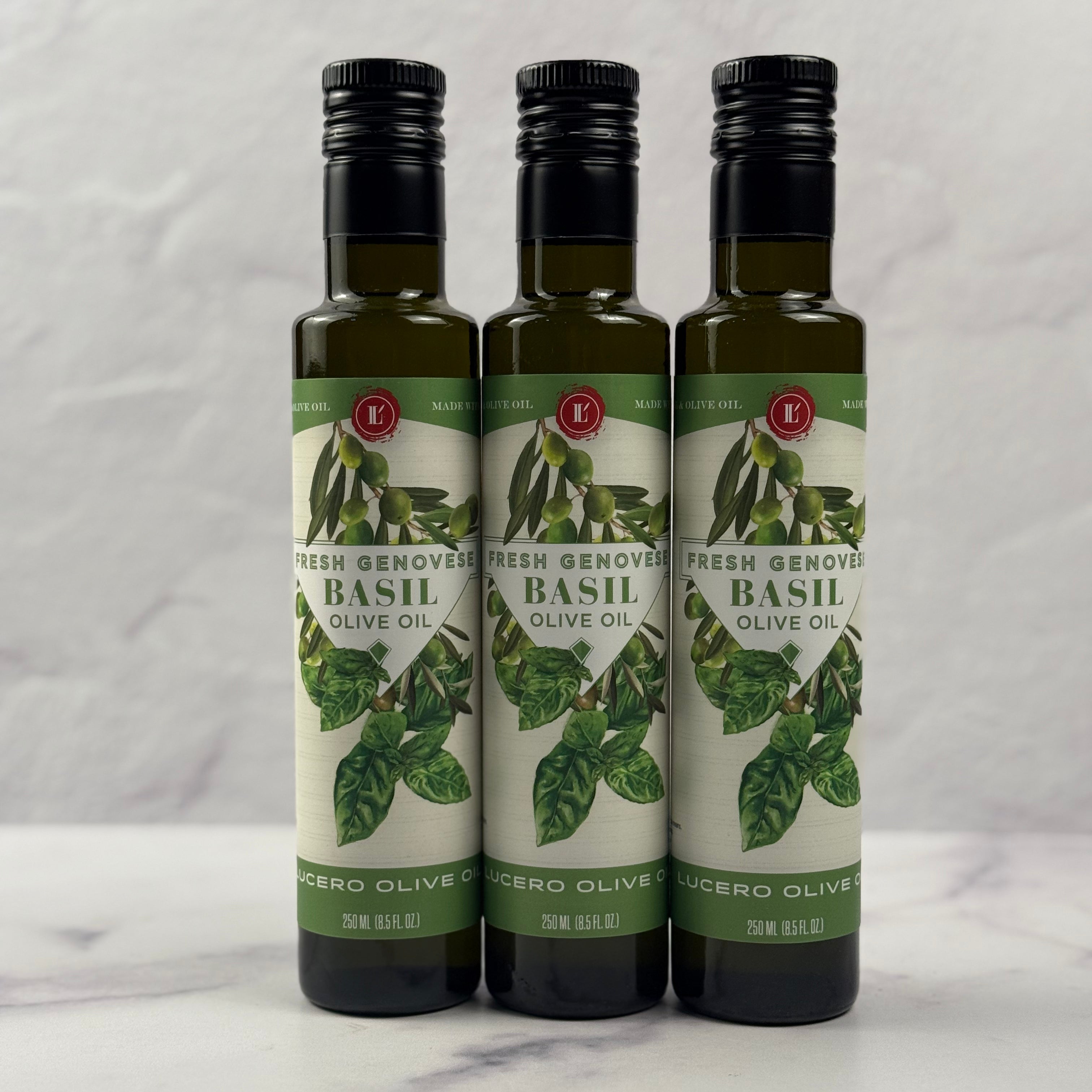 Three 250 ml bottles of Lucero Basil Olive Oil are shown in a marble kitchen