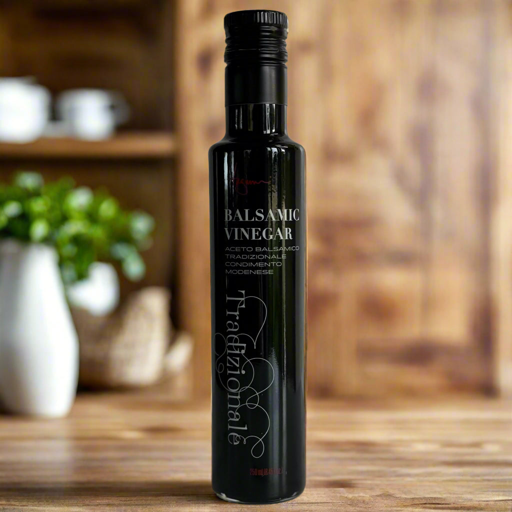 A single 250 ml bottle of balsamic vinegar sits on a warm wooden kitchen counter
