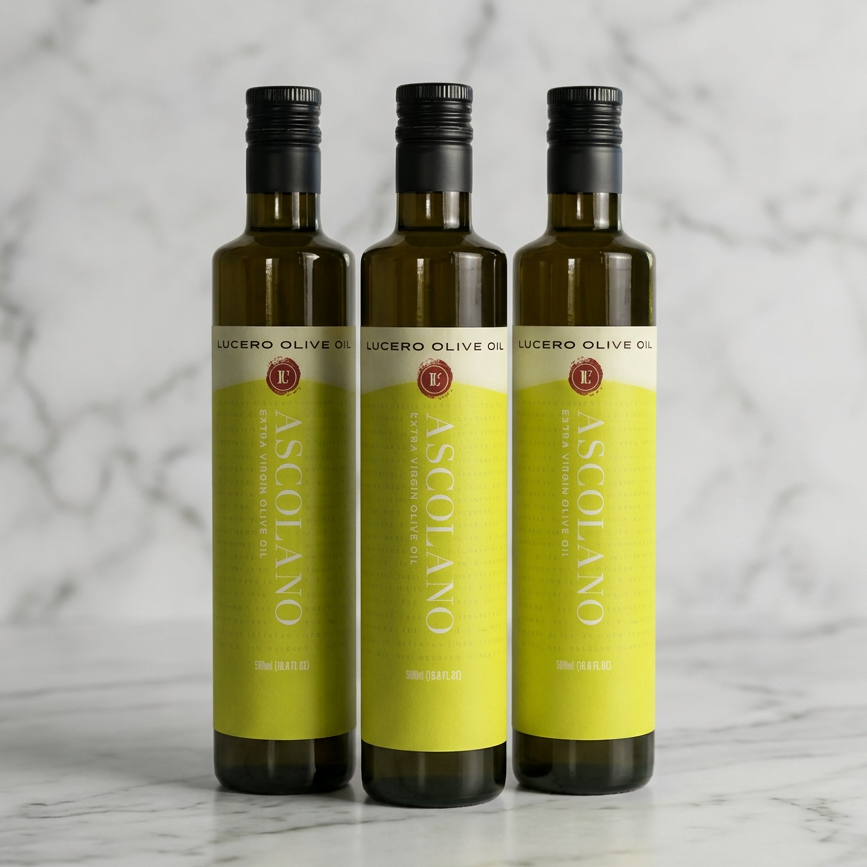Three bottles of Ascolano Lucero Olive Oil arranged side by side on a white marble background.