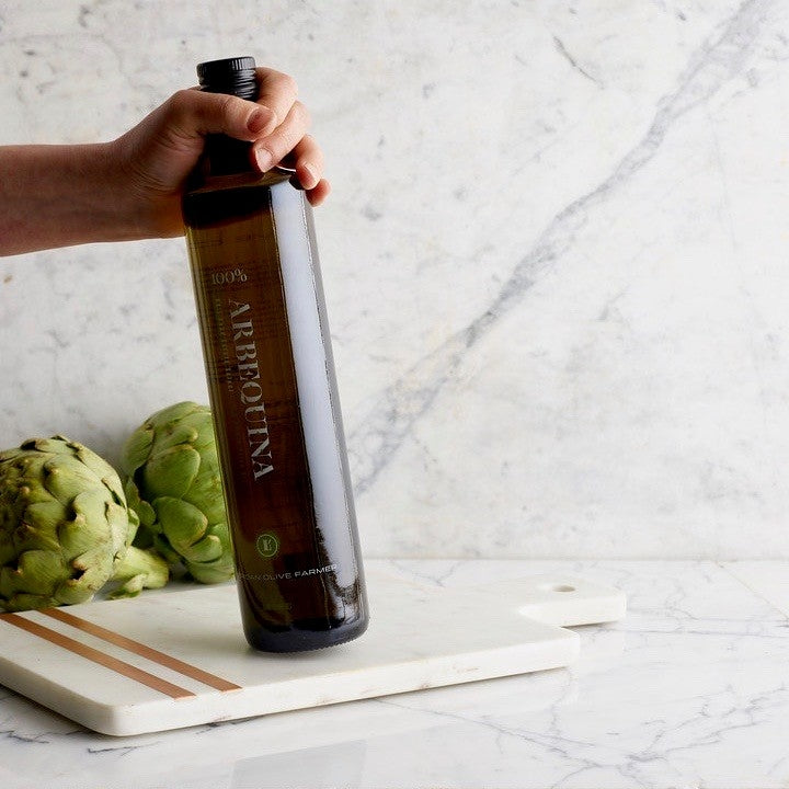 A woman's hand is shown moving a bottle of Lucero Arbequina EVOO as if to take it off-screen