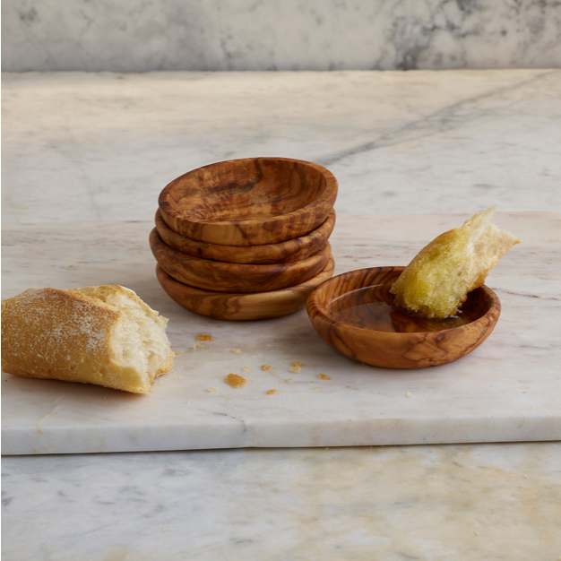 Stack of individual olivewood dipping bowls shown with crusty freshly baked bread and delicious Lucero olive oil
