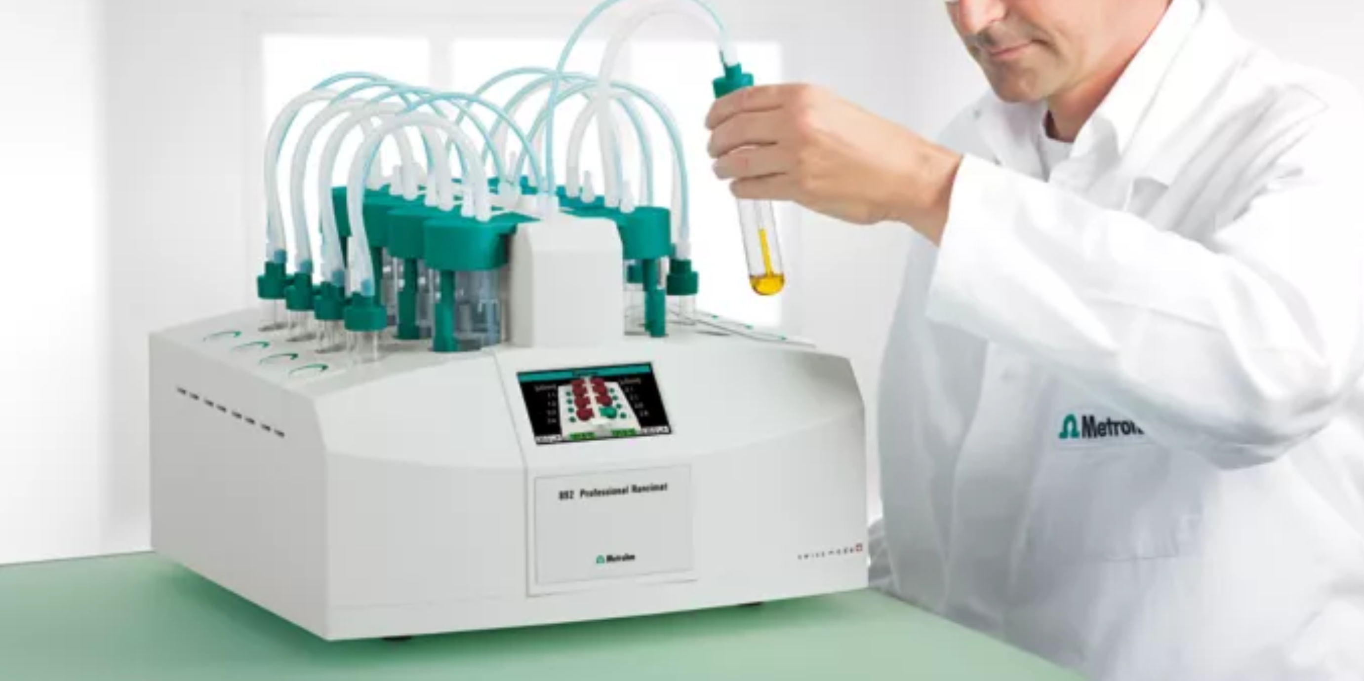 Lab technician in a white coat preparing an olive oil sample for oxidative stability testing using the Rancimat machine.