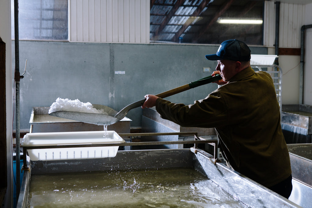Founder and head salt maker, Ben Jacobsen, gently lifts salt from custom evaporation pans