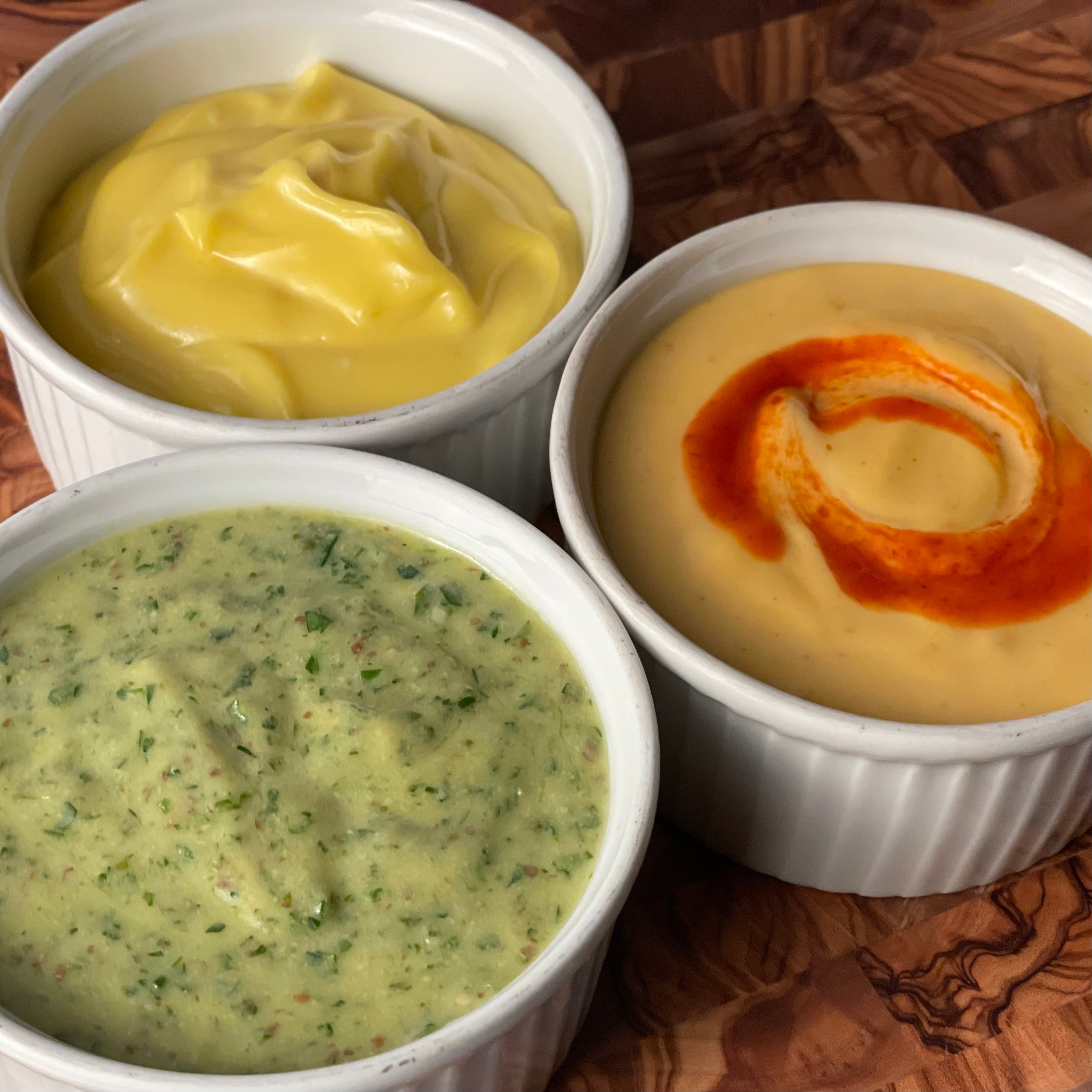 Porcelain ramekins are filled with traditional, herbed, and sriracha mayonnnaise