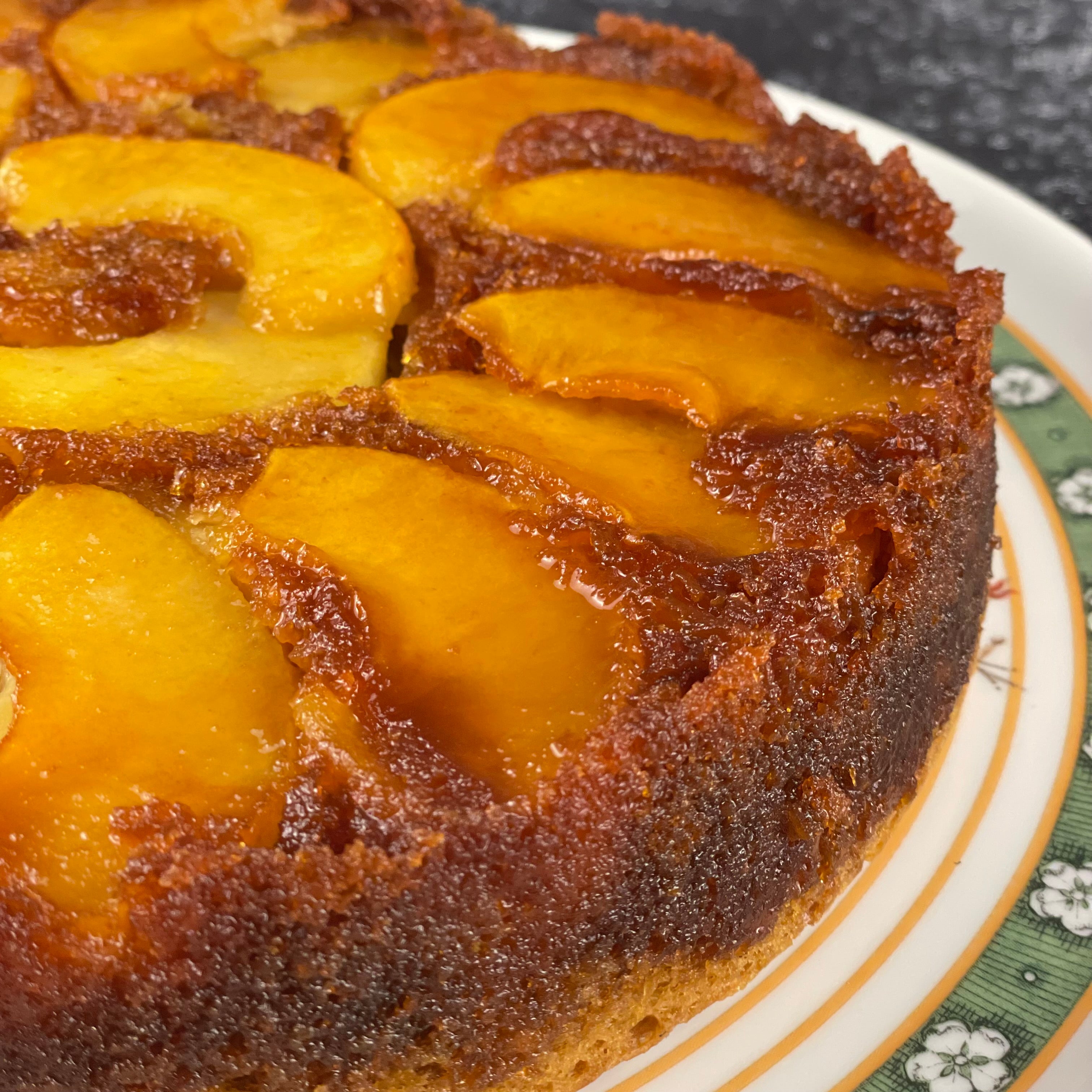 Close up image of caramel soaked olive oil cake festooned with a ring of caramelized apple slices.