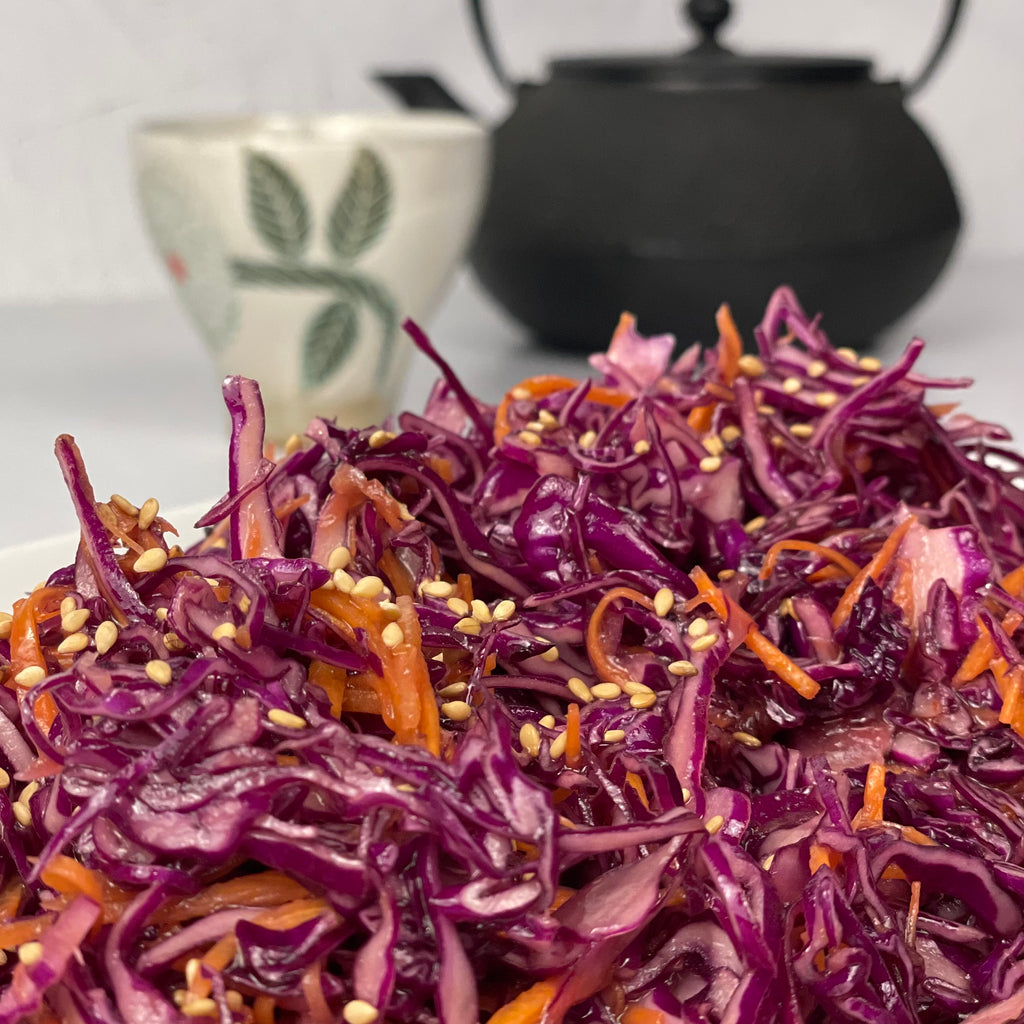 Close up of glossy Miso Cabbage Salad with a Japanese teapot and tea cup in the background