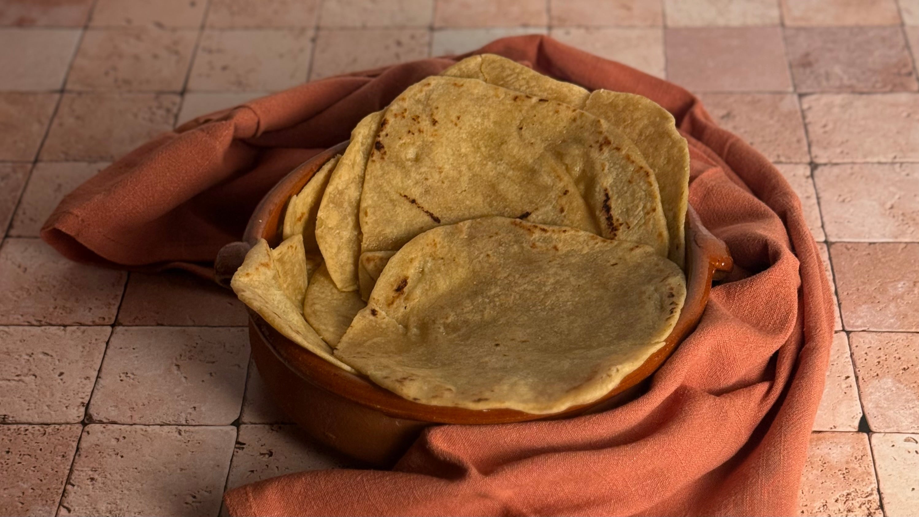 White Sonora Wheat handmade tortillas made with olive oil are placed loosely in a terra cotta cazuela and wrapped in a towel to stay warm.
