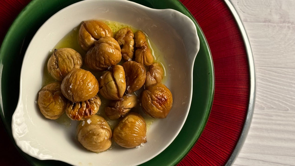 Roasted chestnuts swimming in Olio Novello topped with flake salt crystals in a round French porcelain au gratin