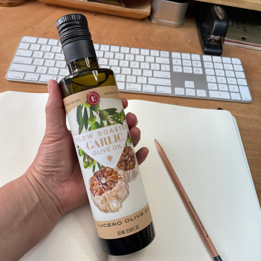 A bottle of Lucero Roasted Garlic Olive Oil at her desk is shown at Liz's desk.