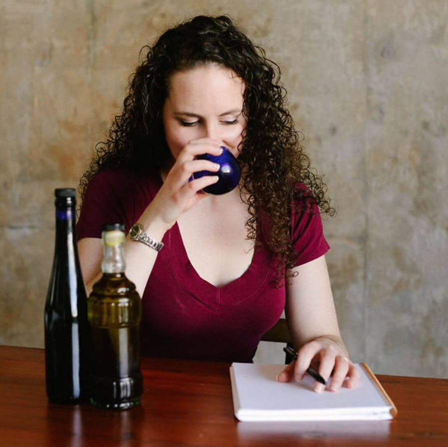 Professional olive oil taster and critic, Emily Lycopolus is shown using an official blue tasting glass to taste olive oil