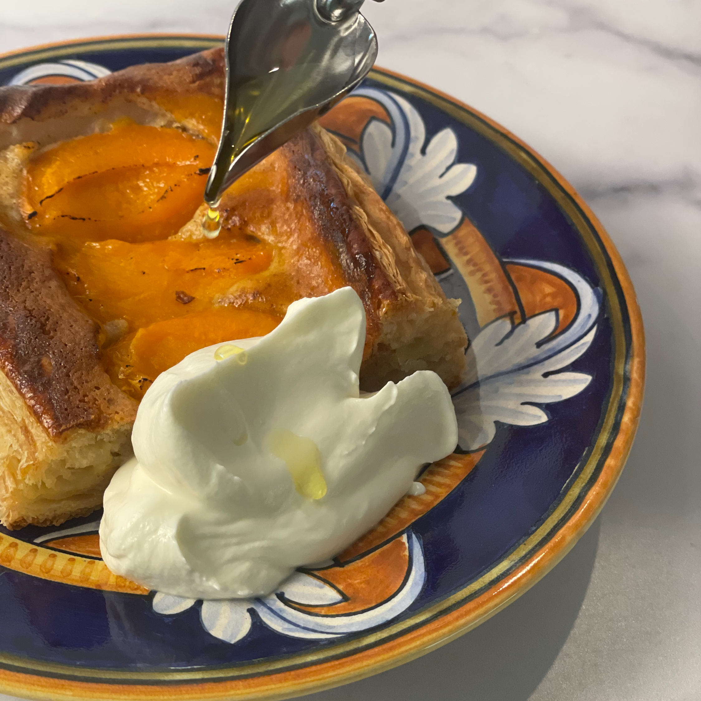 Ascolano EVOO is drizzled onto a rectangular slice of puff pastry with apricots, frangipane, and Ascolano Mascarpone Cream