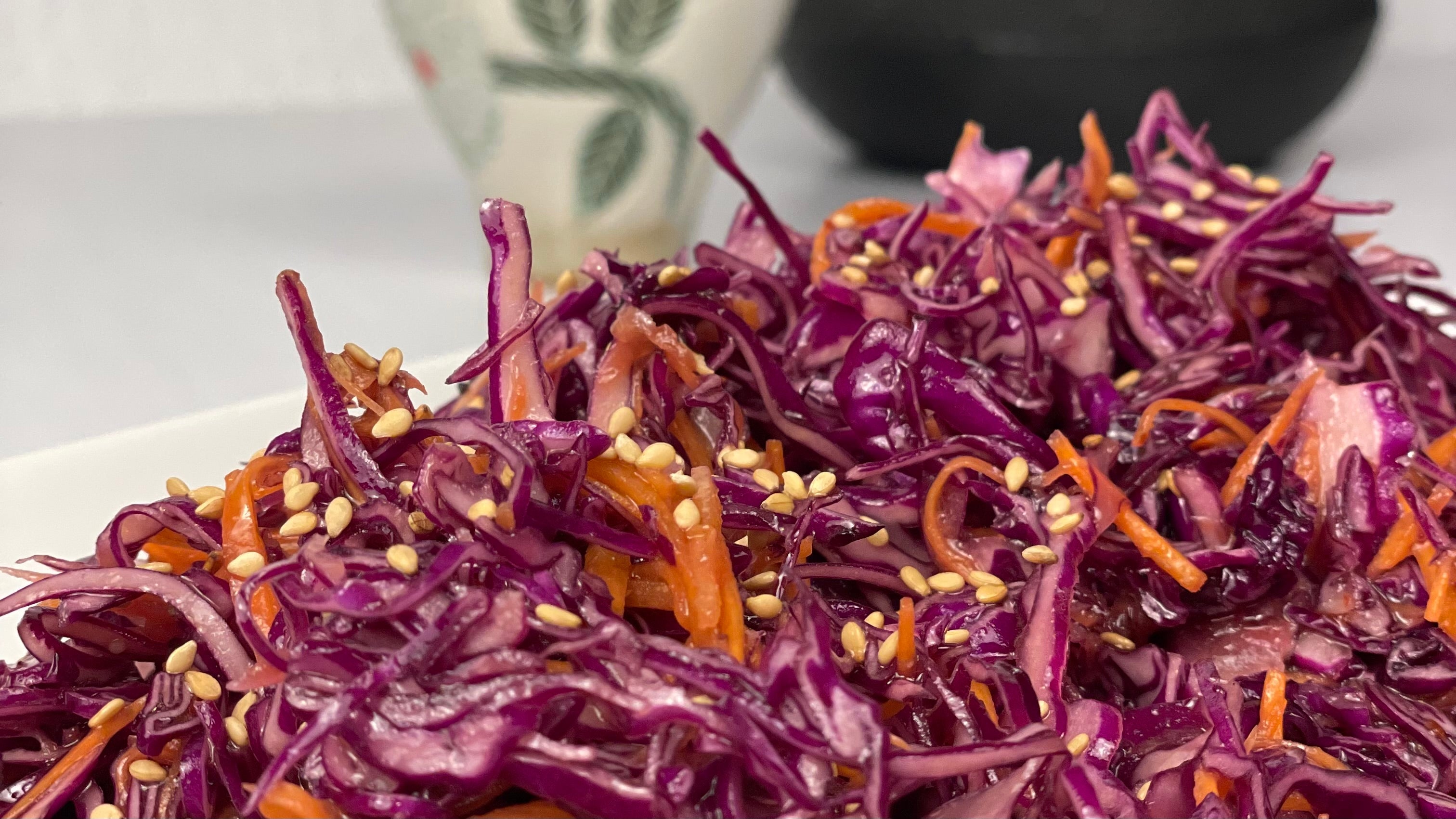 Close up of glossy Miso Cabbage Salad with a Japanese teapot and teacup in the background