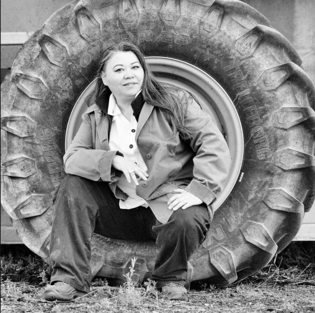 Liz Tagami sits in the giant wheel well of an olive harvester