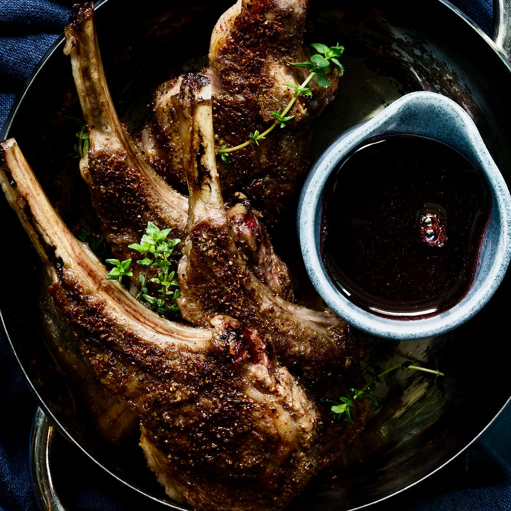 Frenched lamb cutlets (aka lollipops) as shown from above with a cherry gastrique in a separate vessel tucked beside them.