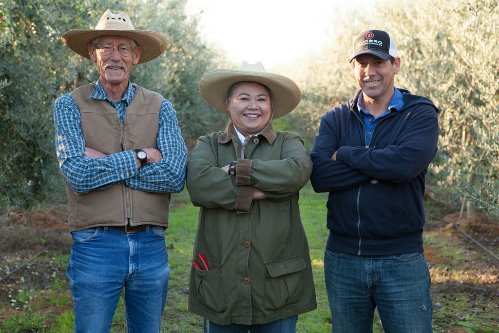 Left to Right, Bob Crane, Liz Tagami, and Brian Crane stand amongst the company's olive trees