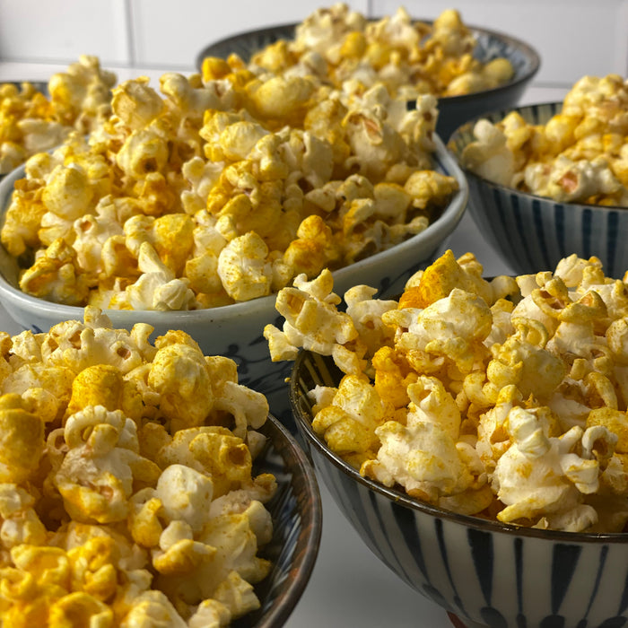 small bowls of different sizes and shapes are filled with Golden Popcorn made with Turmeric Popcorn Seasoning