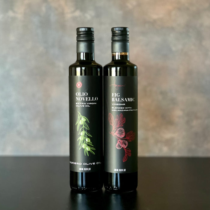 An elegant presentation of Olio Novello and Melanzana Fig Balsamic Vinegar on a warmly inviting yet simple background