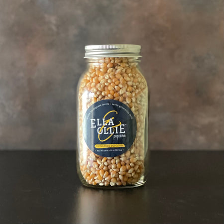 A mason jar of Ella & Ollie Signature Popcorn is shown on a kitchen counter