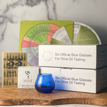 Group image shows 12 boxes of tasting glass with one glass out of box, two tasting wheels, a box of watch glass, and a small tasting notebook.
