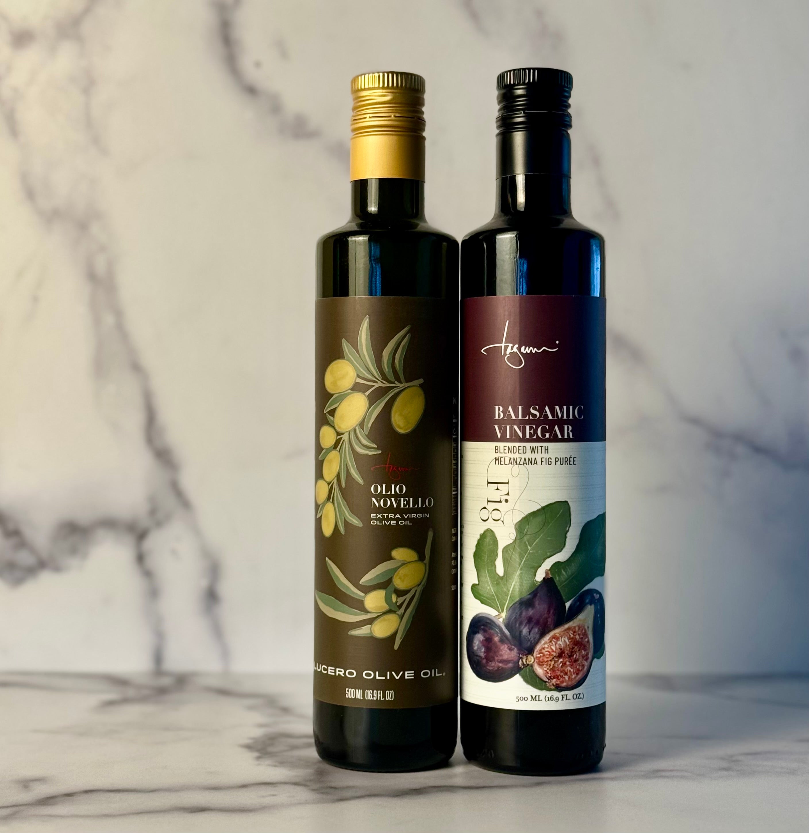 Two bottles of olive oil and balsamic vinegar on a marble surface