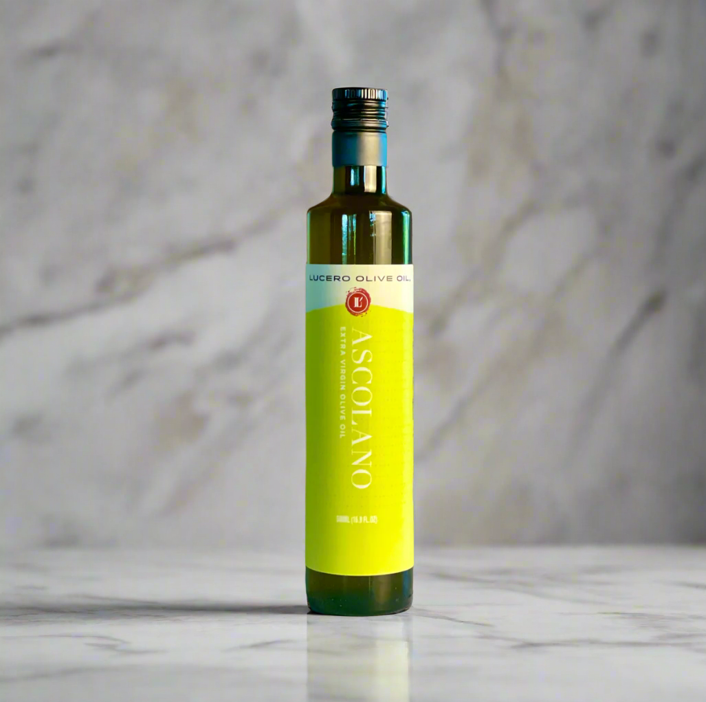 A single bottle of Lucero Ascolano Extra Virgin Olive OIl sits on a copper and marble countertop