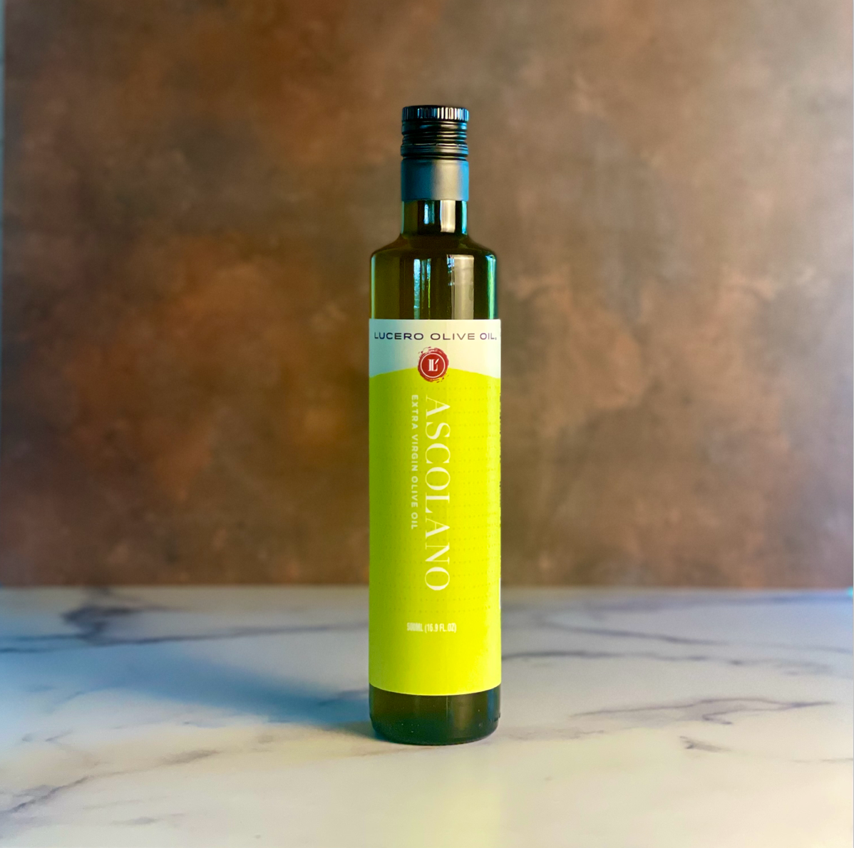 A single bottle of Lucero Ascolano Extra Virgin Olive OIl sits on a copper and marble countertop