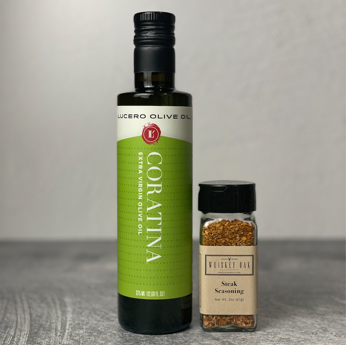 A bottle of Coratina olive oil stands next to a jar of steak seasoning on a kitchen counter