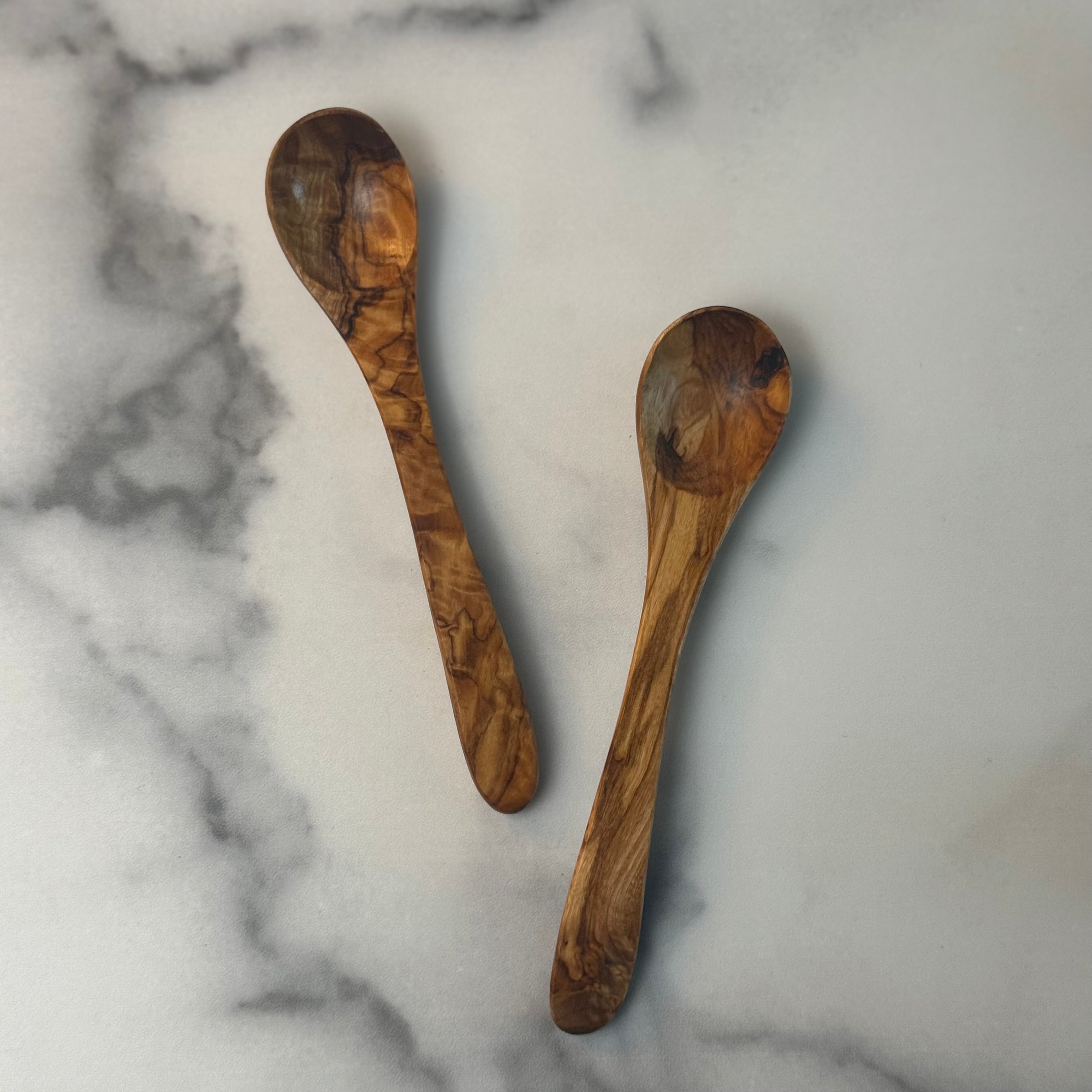 Two wooden spoons on a marble surface