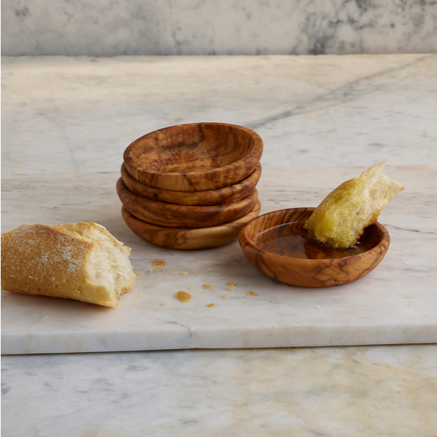 Stack of individual olivewood dipping bowls shown with fresh crusty bread and good olive oil