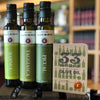The pocket olive oil journal shown with 3 bottles of olive oil in the old (now closed) Lucero Tasting Room.