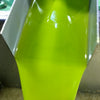 Brilliant translucent green olive oil, freshly milled, flows from the decanter into a holding tank.