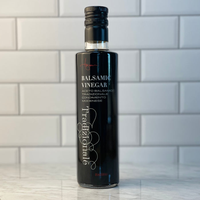 A bottle of traditional balsamic vinegar stands alone on a white marble counter.  Edit alt text