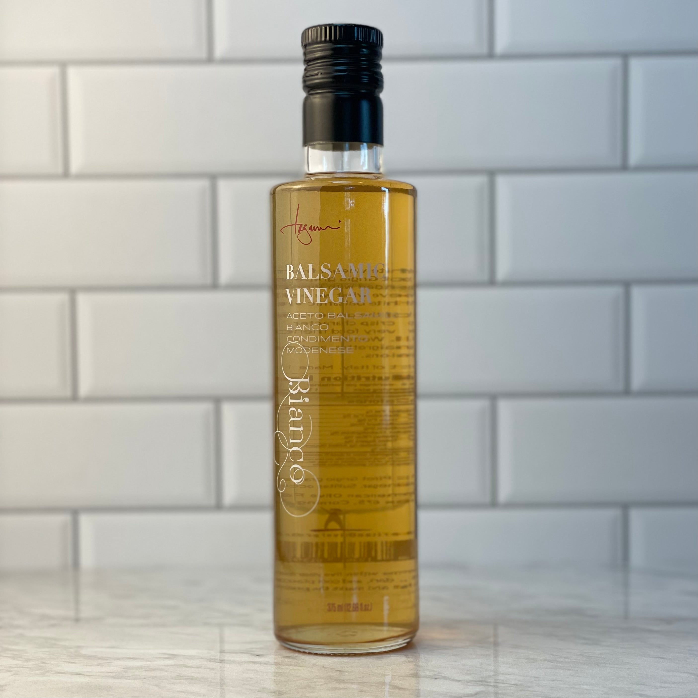 White balsamic vinegar (aka "Bianco"), actually a light golden color, sits on a white marble counter.