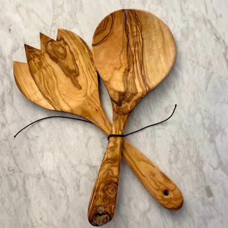 A pair of olive wood salad servers is shown face up tied with black cord to keep them together