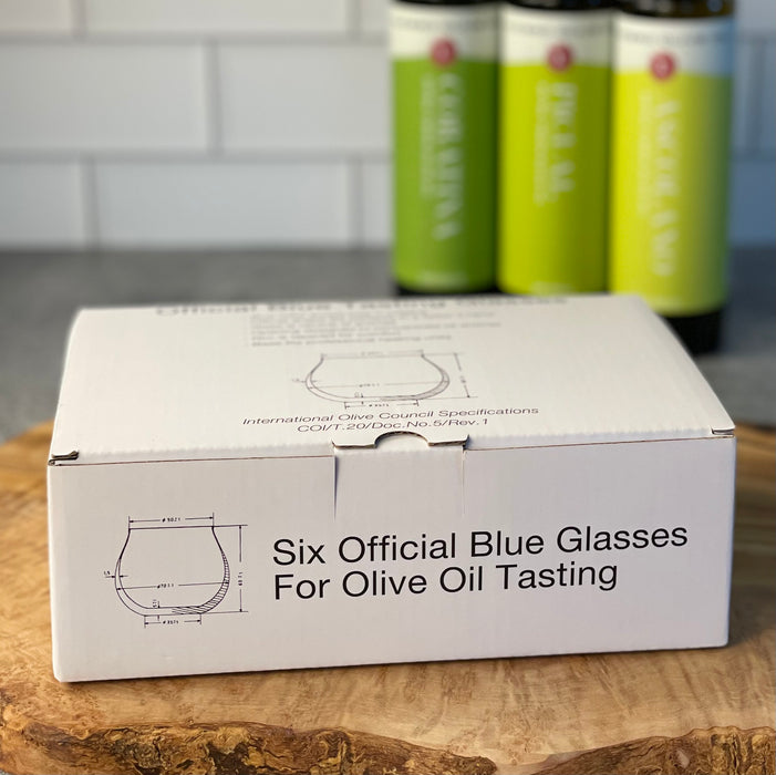 Close up showing the white box holding a set of six blue tasting glasses.