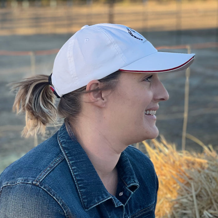 Profile of beautiful young woman smiling while wearing the white American Olive Farmer hat. She is shown in profile so you can see some of the color detail.