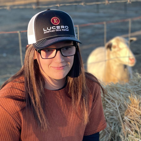 Young woman wears the Lucero Trucker hat while caring for her sheep
