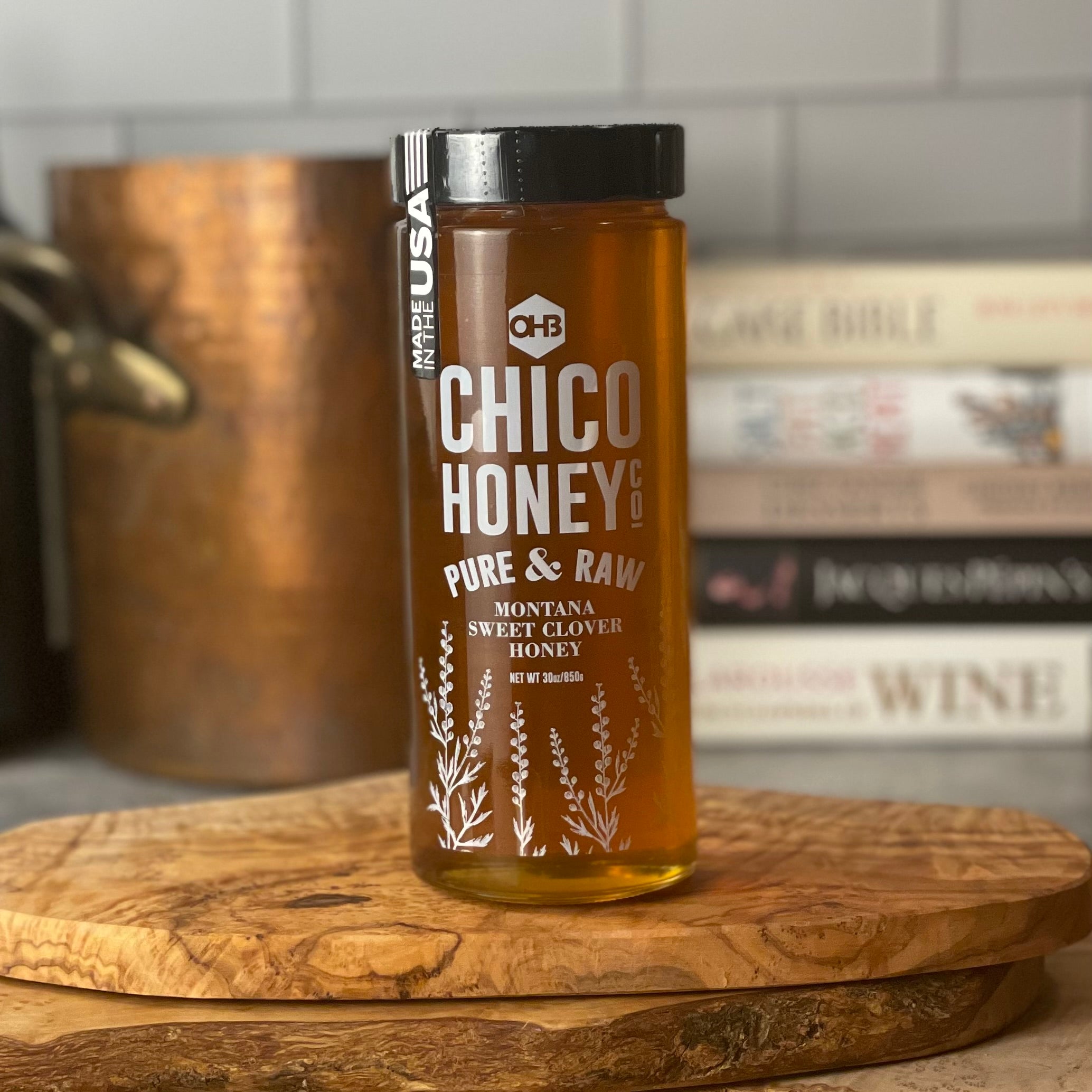 Montana Clover honey, in a large 30 oz jar, shown next to a copper stock pot