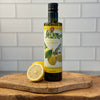 A bottle of Lemon Olive Oil sits on a white marble counter, fresh lemons shown in background.  Edit alt text