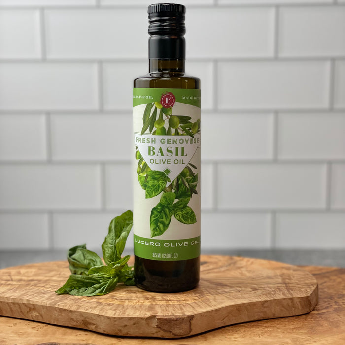 A bottle of Fresh Genovese Basil Olive Oil sits on a marble counter in front of a white tile backsplash.  Edit alt text