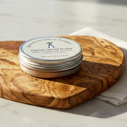 A tin of Kitchen Wood Butter sits in the middle of a heart shaped olivewood on a sunny morning