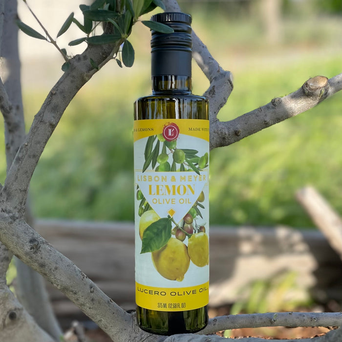 A bottle of Lucero Lemon Agrumato Olive Oil placed in a young olive tree