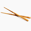 Simple image of a pair of olivewood chopsticks on a white background.