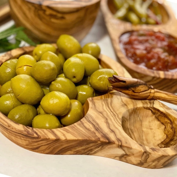 Close up image of green table olives in a carved olivewood olive dish.
