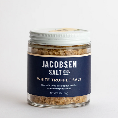 Simple jar of Jacobsen's white truffle salt, crystals clearly visible through the glass above and below the label, sits in a plain white background.