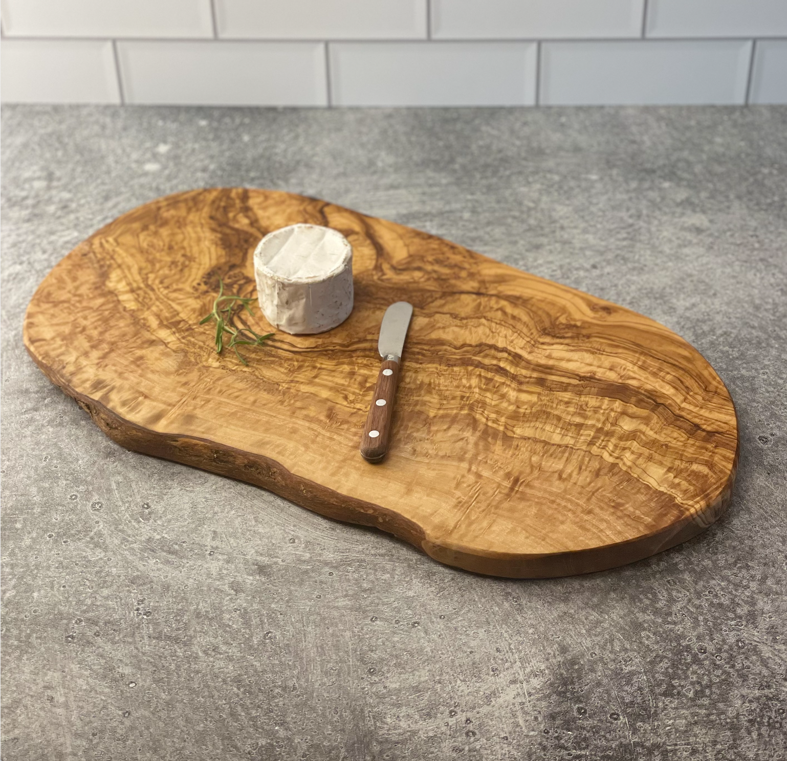 17.5" olivewood board is shown with a small round brie and rosewood handled spreader.