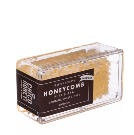 close up image of honeycomb in a clear plastic box. The label indicates "keeper's reserve" and "hand cut" in addition to being pure and raw and Montana Sweet Clover honeycomb.